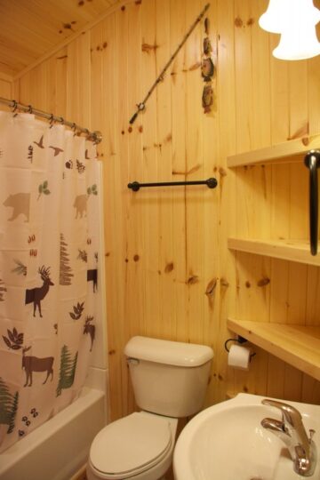 Rustic wood-paneled bathroom with wildlife shower curtain