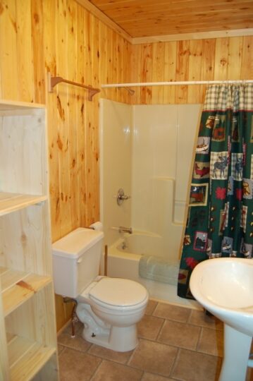Small wood-paneled bathroom with tub and toilet