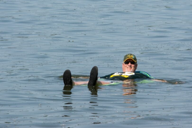 Man floating on lake wearing cap and sunglasses