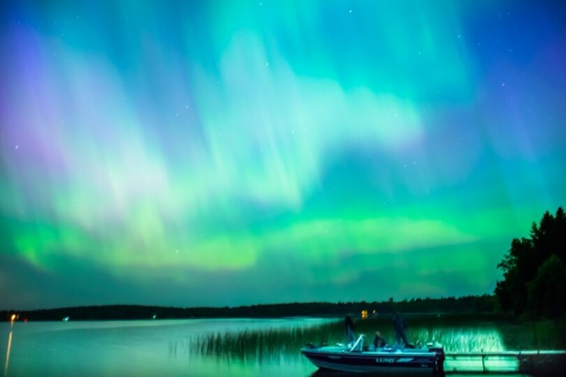 Northern lights over lake with docked boat